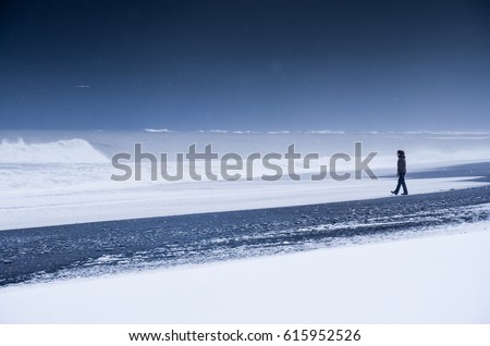Girl walking on the dark beach in Iceland - winter photo with edit space