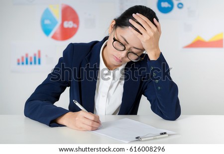 Asian businesswoman wearing suit working at the office, Thinking and writing down on blank paper sheet at the office, Thinking and pay attention and curious situation. Business and finance concepts.