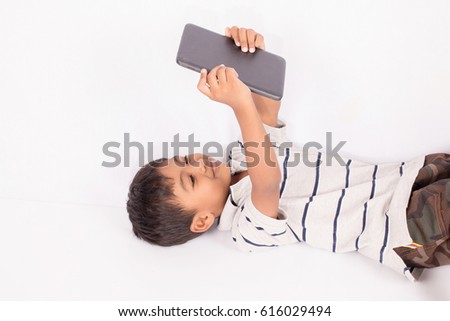 Cute little asian boy lying play tablet on floor