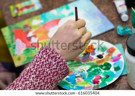 Palette with acrylic paints. Many colors. Lie brushes and palette. Drawing lesson for children and zvroslyh. Creation. Art therapy. The artist paints a picture. Brush in hand. Painting on canvas.