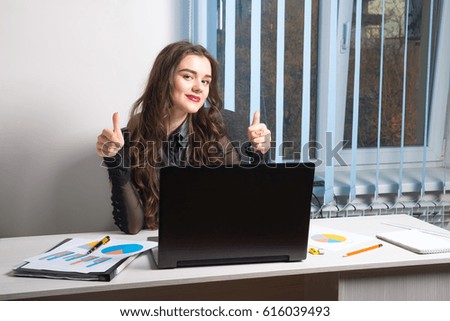 Young  business girl brunette with long hair with laptop in the office Desk. valuable documents, projects, chart, graphics and paper. Manager. vertical. works closely with the document and statistics
