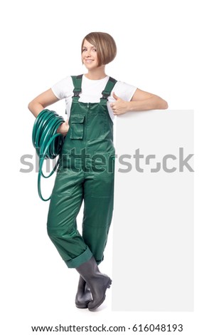 smiling woman professional gardener with garden hose standing next to the banner with empty copy space isolated on white background. advertisement blank board. gardening service and business concept