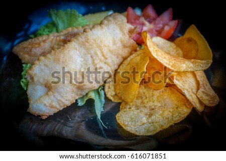 Close up of fish and chips served with a salad of garden-fresh lettuce,tomato and a piece of lemon deep fried battered fish on a plate.