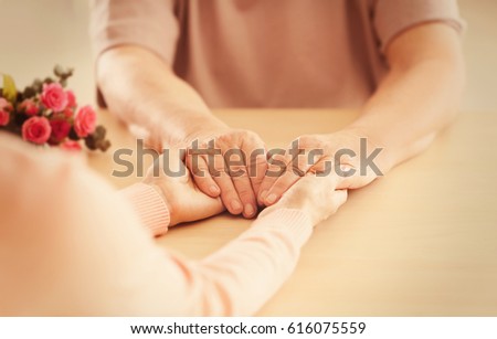 Old and young women holding hands on table