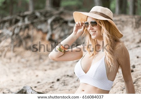 Cropped shot of a young woman wearing sunglasses and a hat sitting on the beach