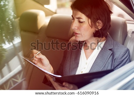Businesswoman signing contract on backseat of the car