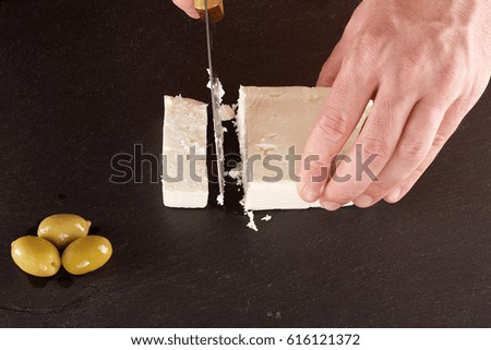 Hand cutting Feta cheese with olives.