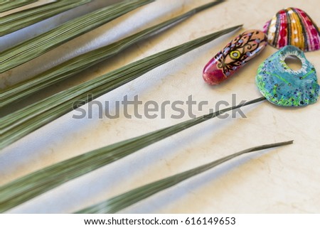 Bright stones sea pebbles and shells with a picture in ethnic, with a palm leaf, fashionable in a modern style, creative images, on a marble surface. Close-up