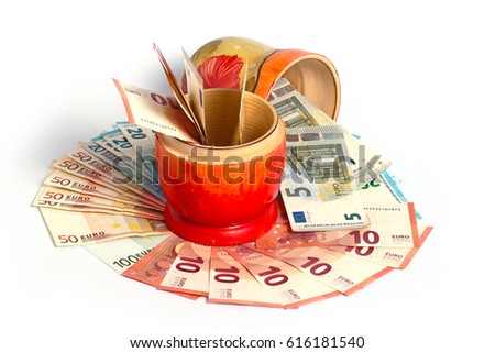 Russian national wooden toy stands on a pile of European paper bills euro