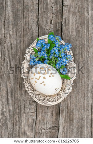 Easter egg and forget me not flowers. Vintage decoration on rustic wooden background