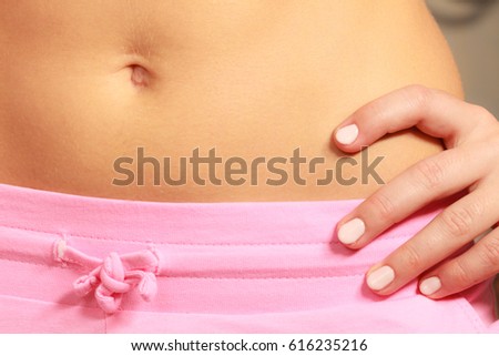 Skincare and bodycare concept. Part body slim fit female belly, perfect abdomen muscles. Woman in pink shorts. Diet aspects.