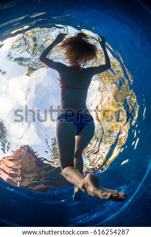 Underwater view of the young woman relaxing in the tropical pool