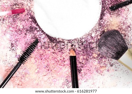 Makeup brush, pencil, lip gloss and other objects, forming a frame on a light background, with crushed powder and copy space. A horizontal template for a makeup artist's business card or flyer design