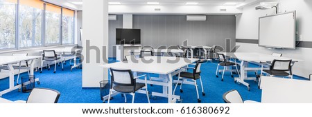 Panorama of modern college group study room with white desks, chairs, big tv screen and board