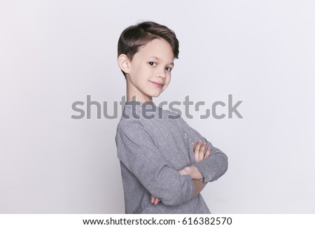 Portrait of young happy smiling brunette boy with crossed hands looking at camera isolated.