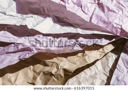Crumpled wrapping craft paper of different colors: pink, white and brown. Layered pieces in the sunlight. Texture for design projects or abstract background with dark shadows
