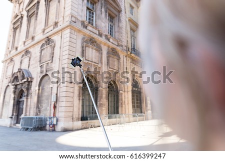 Beautiful blonde woman taking selfie with her selfie stick