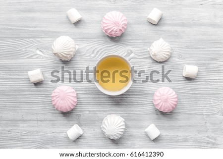 woman breakfast with tea and marsh-mallow light wooden table top view