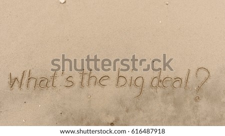 Handwriting  words "What's the big deal?" on sand of beach.