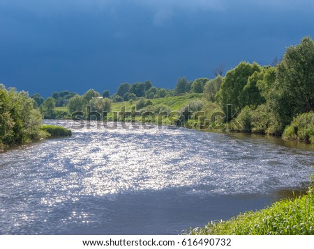 View on Zhizdra River valley in back lit against storm leaden clouds background.