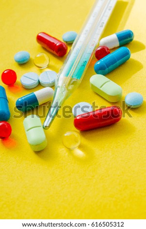 thermometer, pharmaceutical drug , cure, colorful pills and drugs in close up. different tablets on yellow background. Medicine and healthy. Close up of capsules.Vertical photo