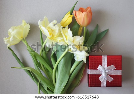 Yellow tulip flowers with red gift box on the table.