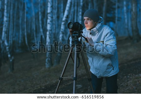 A young photographer takes pictures of the night landscape with a long exposure.