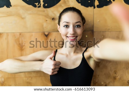Young sporty woman taking a selfie with mobile phone for social networks at gym.