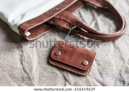 Leather accessory. A purse from genuine leather. Closeup at handmade tanned leather minimalist wallet. Linen fabric background  