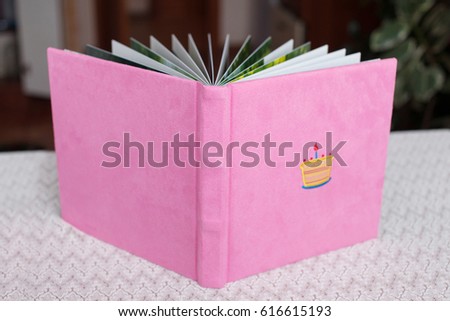 Beautiful photobook in light pink textile cover. Baby photobook with decorative embroidery of birthday cake.   Low depth of sharpness.