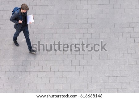 Young man with backpack and headphone going to school college university from above