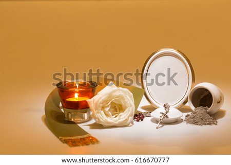 white urn with blank mourning frame, white rose, green tape, candle and rosary for sympathy card on yellow background