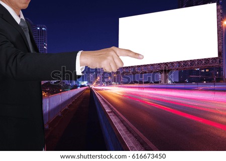 Businessman finger point the blank billboard on the light trails street, city and urban in the night as business, advertisement and goal concept.