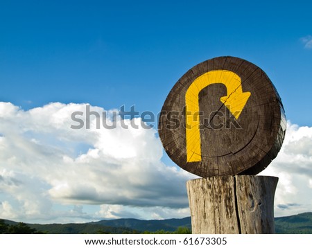 The wooden U turn sign on the top of the hill