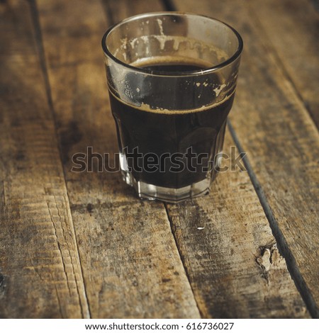 Black coffee in a transparent glass on a wooden surface
 