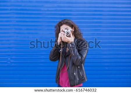 portrait a young beautiful woman holding a vintage camera over blue background. LIfestyles