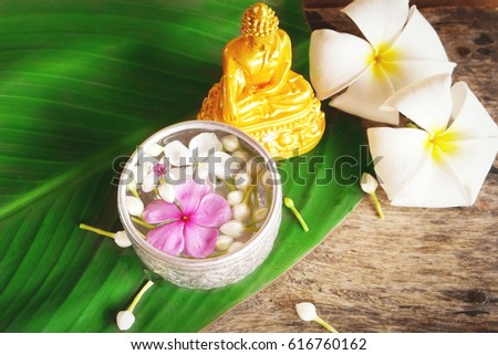 Songkran festival background. water blessing ceremony for Buddha statue on wooden table with green leaf , copy space
