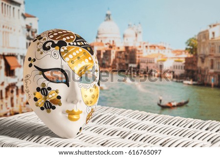 Venetian mask with Canal Grande and Santa Maria della Salute church in the background. Traditional souvenir and beautiful view to the city and a gondolier in a gondola. Sunny Venice travel concept