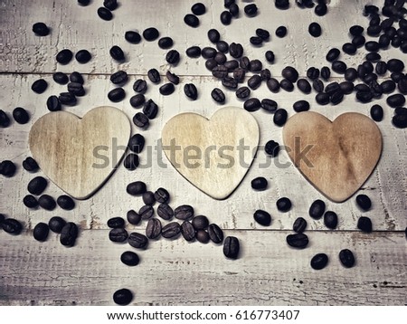 Three wooden cartoon heart placed nicely on the white background and coffee beans spread around them, in vintage style,for tell love someone or symbol who love coffee.  