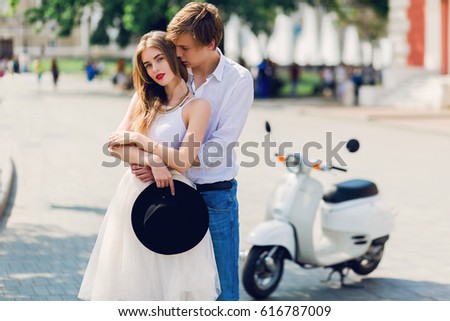 Attractive romantic couple enjoying walk together in old European city . Soft tone photo. Retro whit scooter on background. 
