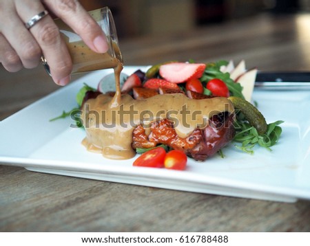 Pouring signature dressing onTasty smoked Duck breast with mixed salad
