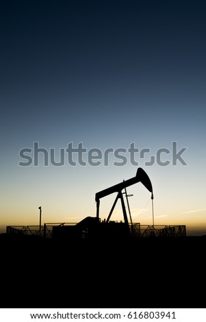 Silhouette of bpu crude oil pump in oilfield at sunset 