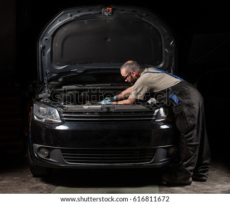 mechanic fixing a car at home Royalty-Free Stock Photo #616811672