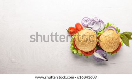 Hamburger with cheese, meat, tomatoes and onions and herbs. On Wooden background. Top view. Free space.