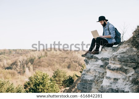 handsome bearded man freelancer working on a laptop outdoors in mountains. Freelance concept Royalty-Free Stock Photo #616842281