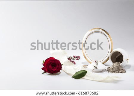 white urn with blank mourning frame, red rose, white tape  and rosary for sympathy card on bright background
