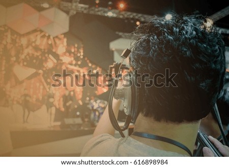 Back view of Video Camera ,has focus behind the photographer and headphone for broadcasting and recording,in live concert ,vintage tone