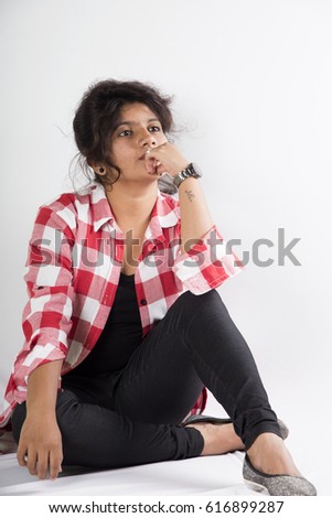 Happy young girl sitting on the floor, isolated on white background.