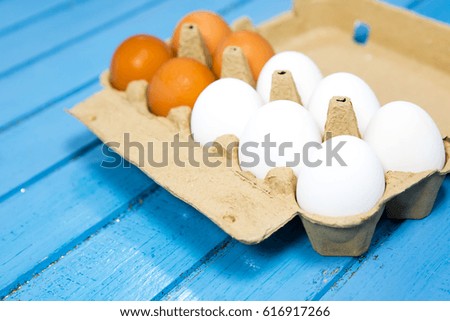View of opened box of chicken eggs, blue background