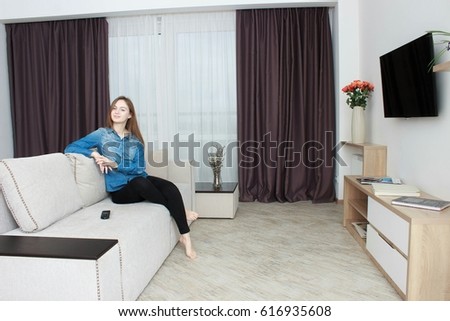 Young woman In black pants and a blue shirt watching TV